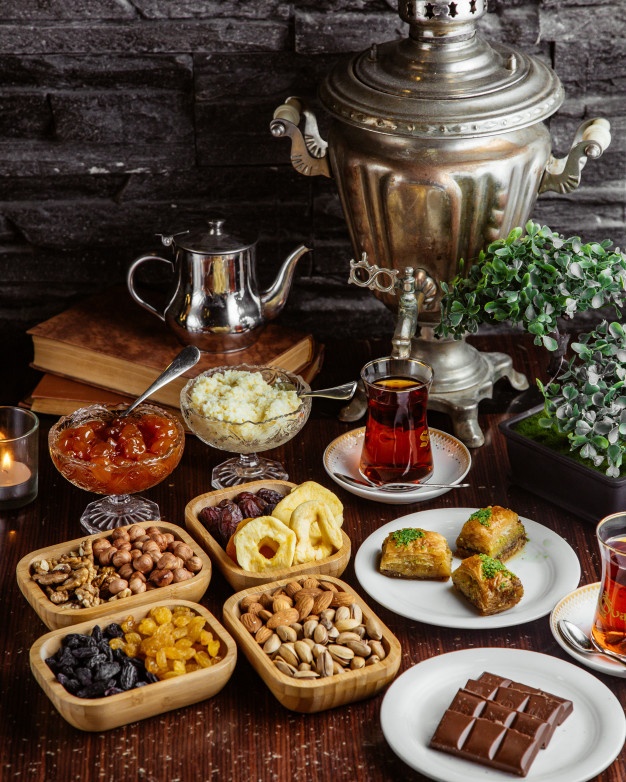 front-view-samovar-teapot-sweets-tea-set-chocolate-bar-pistachios-dried-fruits-baklava-with-two-glasses-armudu_140725-11419